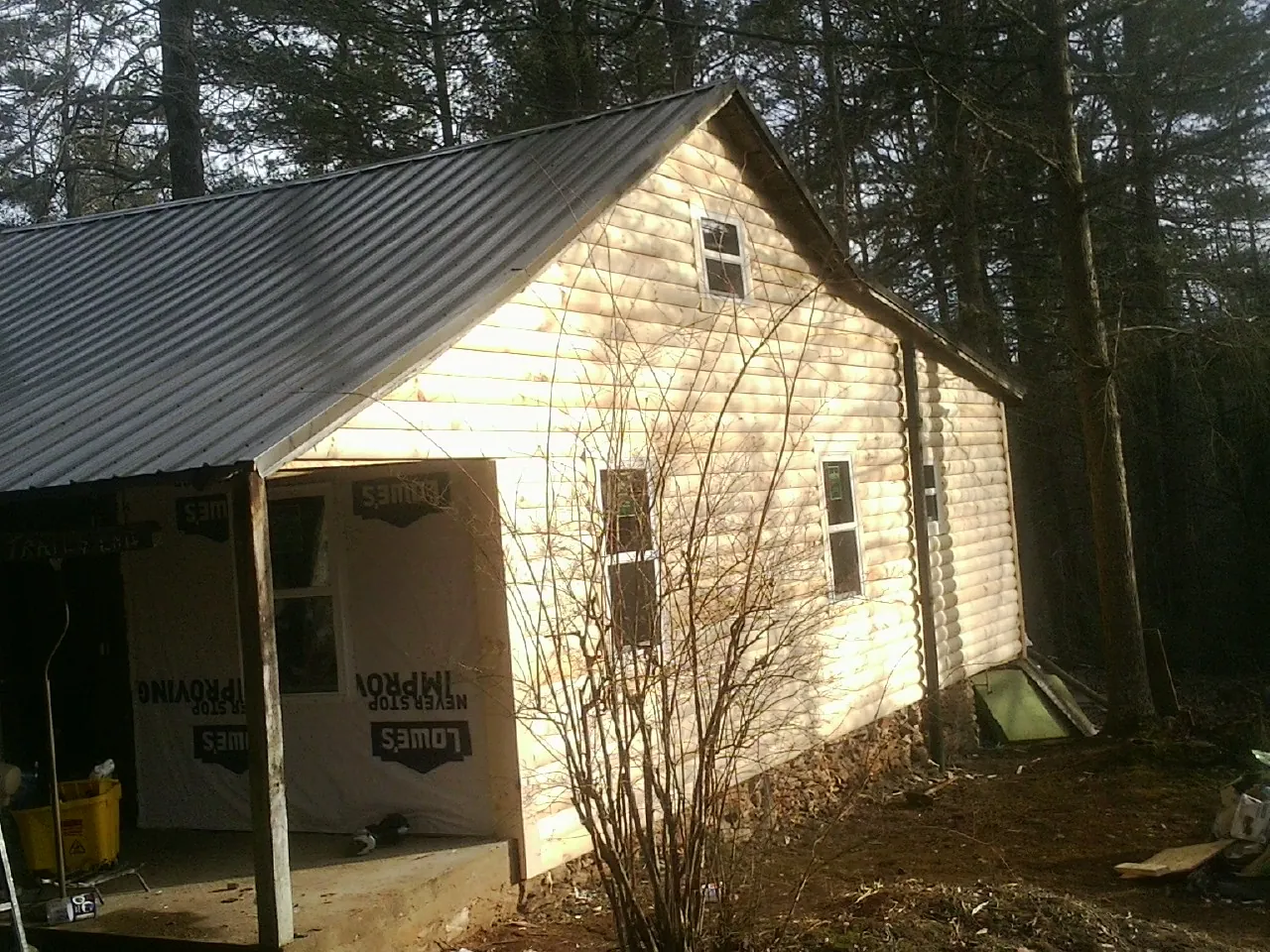 Log siding gable end under a dark metal roof edge in Liberty